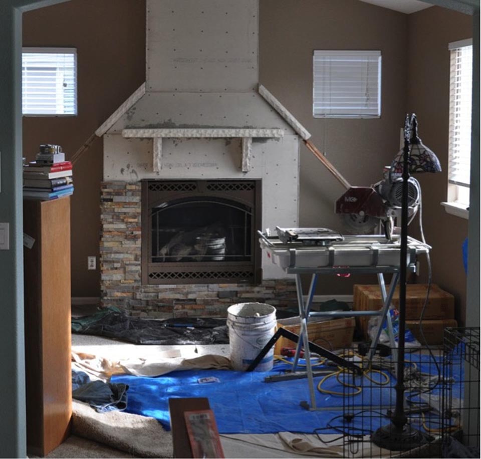 In process installation of stacked stone on a fireplace where a tile wet saw is being used to make the cuts